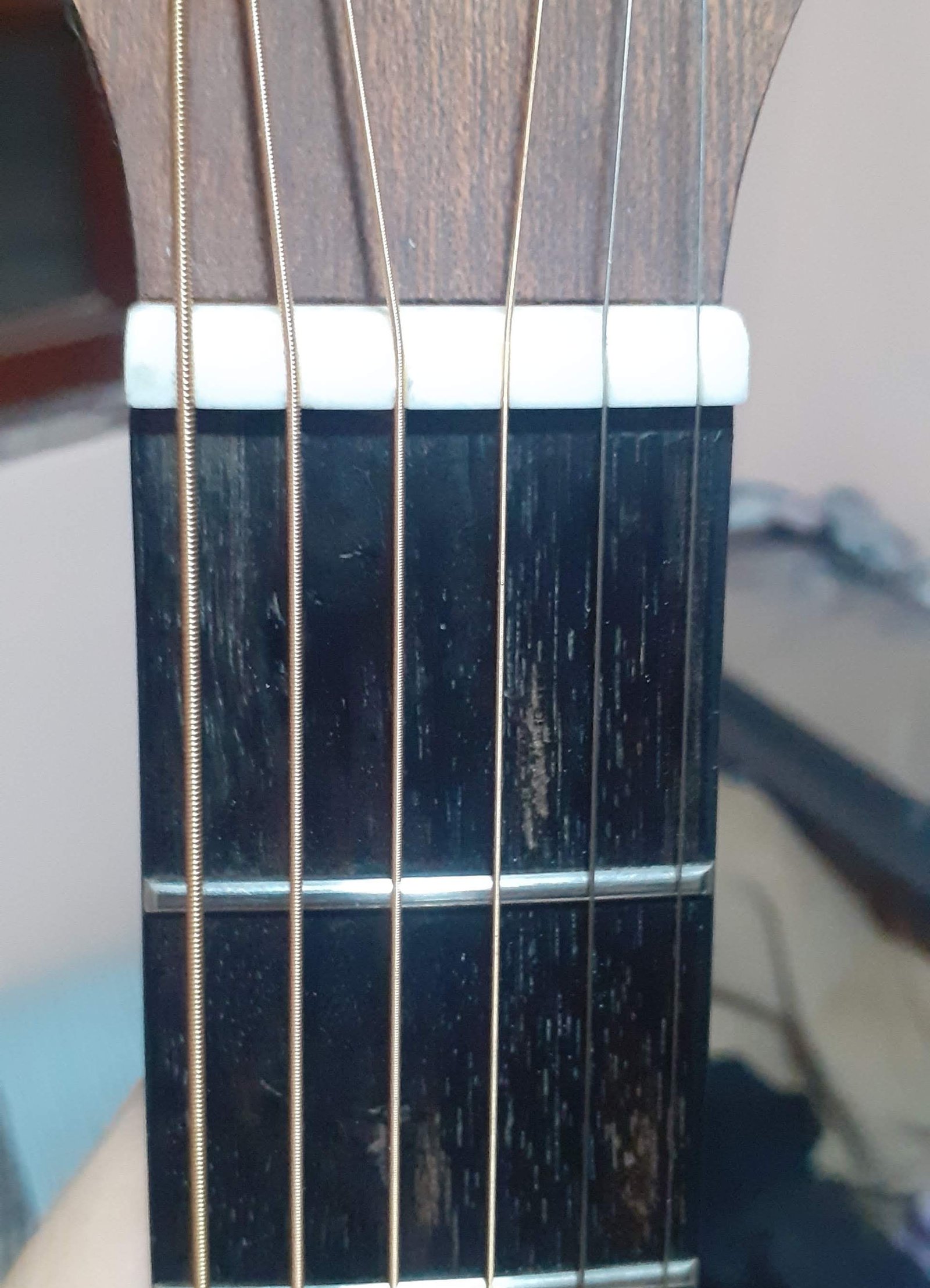 Pestana de osso recém-instalada no braço do violão, com as seis cordas apoiadas