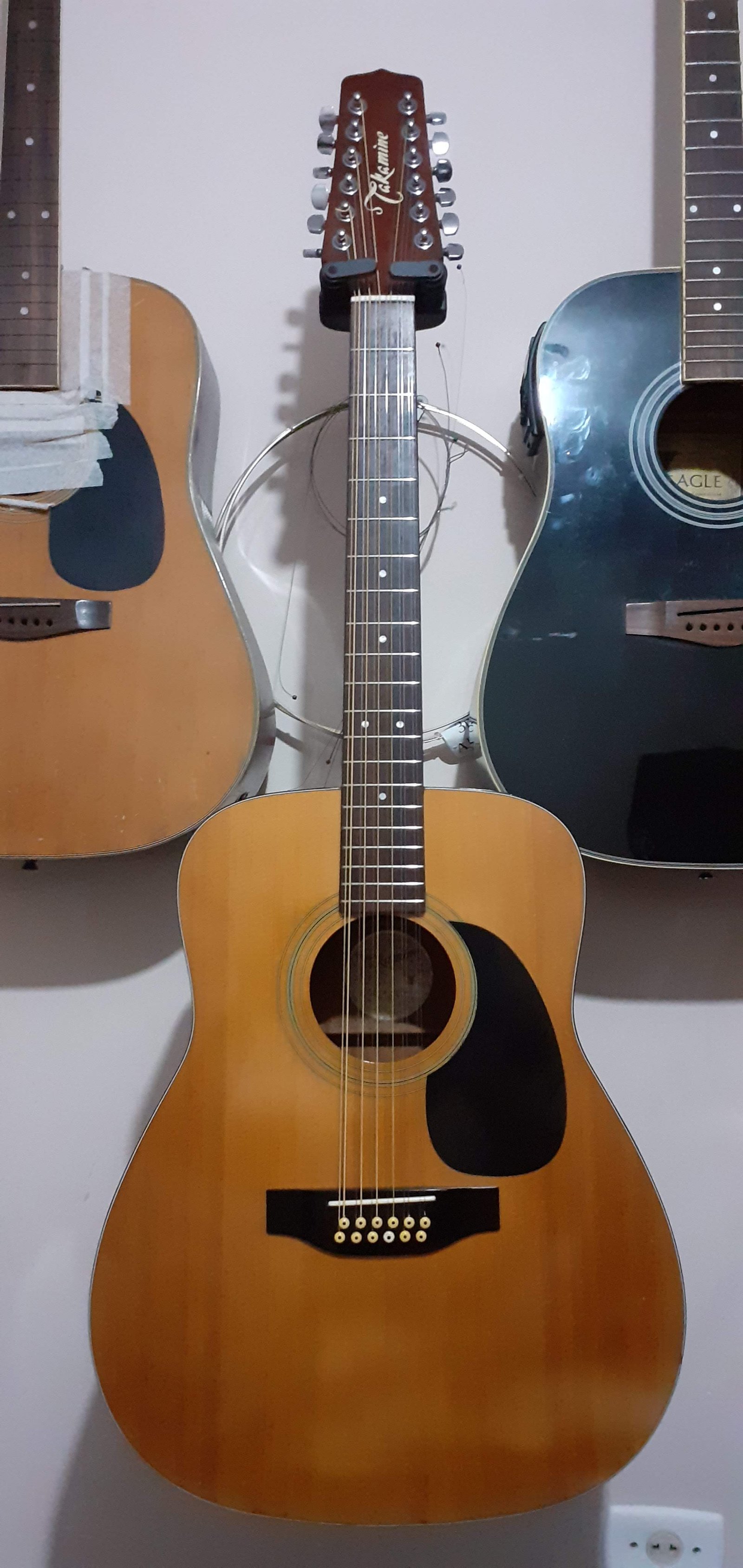 Violão Takamine 12 cordas apoiado ao lado de outros violões na oficina